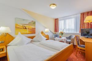 バート・クロツィンゲンにあるEden Hotelのベッドとデスクが備わるホテルルームです。