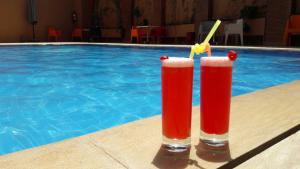 two red cocktails sitting next to a swimming pool at Blue Sea Le Printemps in Marrakesh