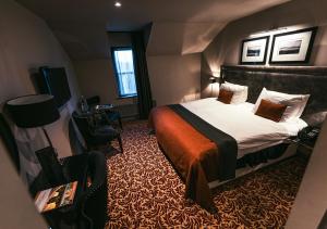 um quarto de hotel com uma cama e uma cadeira em The Fenwick Hotel em Kilmarnock