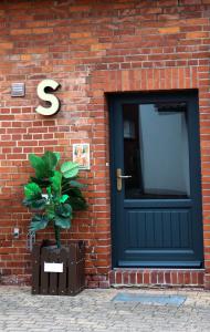 a brick building with a black door and a plant at Planet Gast - Beatles-Wohnung in Marklohe