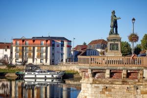 ein Boot auf einem Fluss neben einer Statue in der Unterkunft ibis Auxerre Centre in Auxerre