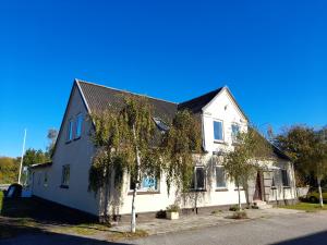 Una casa blanca con un árbol delante. en Købmandsgaardens B&B en Gedser