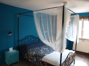 een slaapkamer met een hemelbed en witte gordijnen bij Slaaphuisje Het vliegend varken in Genk