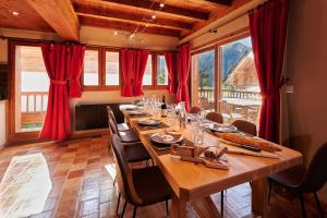 uma sala de jantar com uma mesa longa e cortinas vermelhas em Chalet HERRISSON Peisey- Vallandry - Domaine Paradiski em Peisey-Nancroix