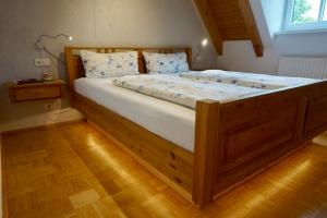 uma grande cama de madeira num quarto com piso de madeira em Weinhof Grosch em Sugenheim