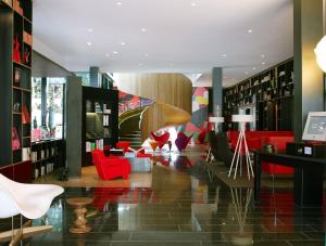 uma biblioteca com cadeiras vermelhas e estantes em citizenM London Bankside em Londres