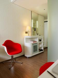 Zimmer mit einem roten Stuhl und einem Spiegel in der Unterkunft citizenM London Bankside in London