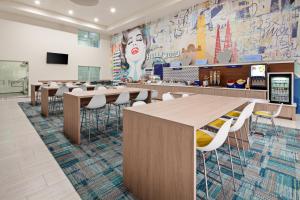 a cafeteria with tables and chairs and a mural at Holiday Inn Express Hollywood Walk of Fame by IHG in Los Angeles