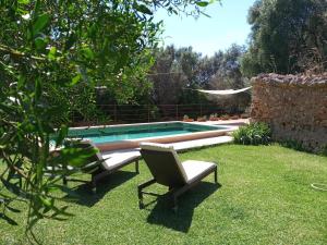 a swimming pool with two chairs in a yard at Finca Cas Canar in Sencelles