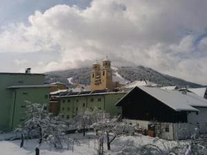 ein Gebäude mit einem Uhrturm im Schnee in der Unterkunft Gästehaus Maria in Steinach am Brenner