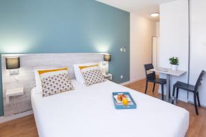 um quarto com uma grande cama branca e uma mesa em Zenitude Hôtel-Résidences Le Tholonet em Aix-en-Provence