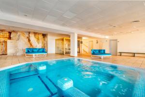 a large swimming pool with blue chairs in a room at Hotel Na Forana in Cala Ratjada