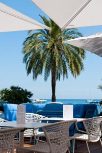 a table and chairs with a palm tree in the background at Hotel Victoria in Roquebrune-Cap-Martin