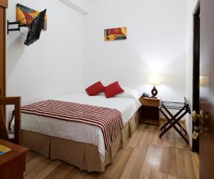 ein Schlafzimmer mit einem Bett und einem Tisch mit einer Lampe in der Unterkunft Hotel Samaña in Arica