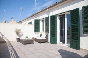 a patio with green shutters on a white building at Long House Ses Salines in Ses Salines