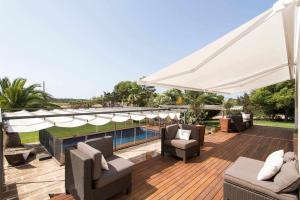 Una terraza de madera con sillas y una sombrilla blanca. en Casa con piscina privada en el sur de Mallorca, en Ses Salines