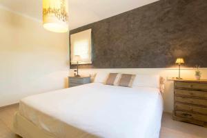 Un dormitorio con una gran cama blanca y dos lámparas. en Casa con piscina privada en el sur de Mallorca, en Ses Salines 28 fotos más