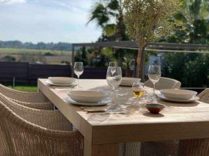 Una mesa con copas de vino y platos encima. en Casa con piscina privada en el sur de Mallorca, en Ses Salines