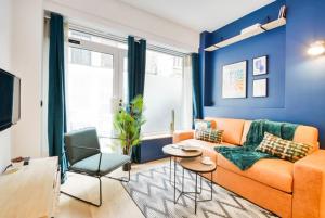 sala de estar con sofá naranja y pared azul en New and renovated amazing flat in heart of PARIS, en París