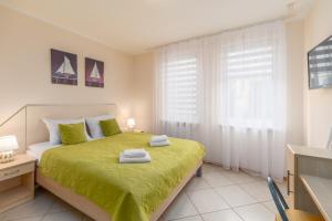 a bedroom with a green bed with a window at Apartment Bielik A01 by Renters in Międzyzdroje