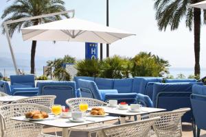 a patio with tables and chairs and the ocean at Hotel Victoria in Roquebrune-Cap-Martin