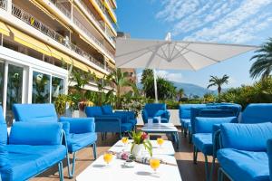 a patio with blue chairs and an umbrella at Hotel Victoria in Roquebrune-Cap-Martin