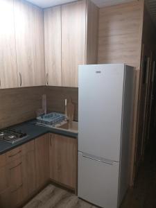 グロジスク・マゾビエツキにあるDomek Dwupokojowy N4 - FreezerHause Kozery- NoclegiGrodziskPL 792-535-535の白い冷蔵庫付きのキッチン(木製キャビネット付)