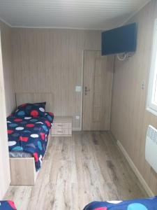 een kleine slaapkamer met een bed en een houten vloer bij Domek Dwupokojowy N4 - FreezerHause Kozery- NoclegiGrodziskPL 792-535-535 in Grodzisk Mazowiecki