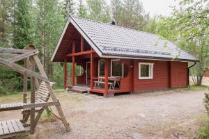 eine kleine rote Hütte im Wald mit einer Veranda in der Unterkunft Loma Rinteelä in Suonenvaara
