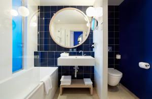 een badkamer met een bad, een wastafel en een spiegel bij Hotel Victoria in Roquebrune-Cap-Martin