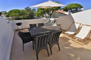 ヴァーレ・ド・ローボにあるCasa Vale Do Lobo 832A - Charming Townhouse AC few minutes walk from Beach Pracaのバルコニー(ブラックテーブル、椅子、パラソル付)