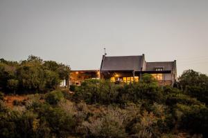 una casa en la cima de una colina con árboles en African Safari Lodge, en Grahamstown