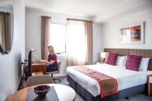 a woman sitting at a desk in a hotel room at Quest Toowoomba in Toowoomba