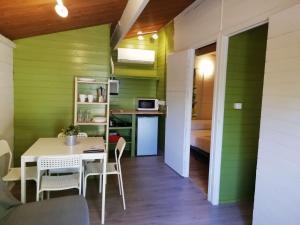 Camping la Pedrera في Bigastro: غرفة طعام بجدران خضراء وطاولة وكراسي