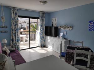 a living room with blue walls and a tv and a table at Apartamento LE SOLEIL Complex Amaya Fuerteventura in Costa de Antigua