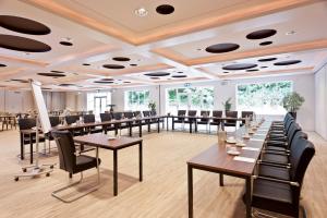 a dining room with tables and chairs and windows at Fletcher Hotel-Restaurant Teugel Uden-Veghel in Uden