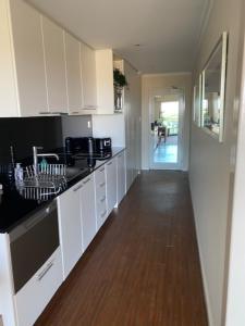 a kitchen with white cabinets and a wooden floor at Dolphin View 404 in Mandurah