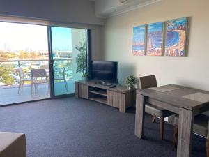 sala de estar con mesa, TV, mesa y sillas en Dolphin View 404, en Mandurah