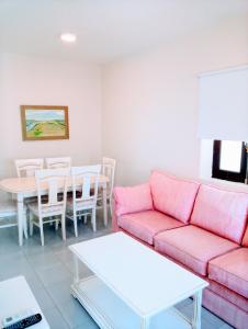 Apartamentos Larga 70 في إل بويرتو دي سانتا ماريا: غرفة معيشة مع أريكة وردية وطاولة
