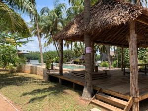 Natura luxury red house في Ouidah: سطح خشبي مع كوخ مع مسبح