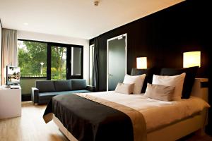 - une chambre avec un grand lit et un canapé dans l'établissement Fletcher Hotel-Restaurant Teugel Uden-Veghel, à Uden