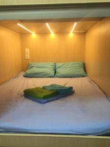 Una cama con dos toallas verdes encima. en Boxtel Hostel, en Moscú