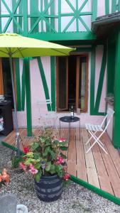 a patio with a table and an umbrella and flowers at Le Jardin des Merveilles in Saint-Pierre-dʼAutils