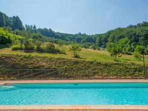 Serravalle Pistoiese的住宿－Apartment Crepuscolo by Interhome，一座树木繁茂的山丘前的游泳池