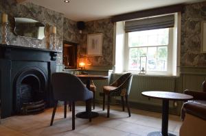 a living room with a fireplace and a table and chairs at The Forresters Arms Kilburn in Kilburn