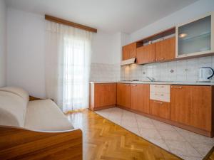 a kitchen with wooden cabinets and a couch in a room at Apartment Fuma-3 by Interhome in Jadranovo