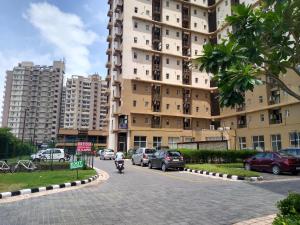 a man riding a motorcycle down a street next to a tall building at Entire Condominium Luxury Suites Perfect Getaway in Noida
