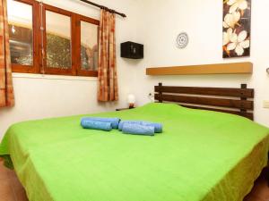 Una cama verde con dos almohadas azules. en Apartment Adelfa apt- 1 by Interhome, en Sant Martí d’Empúries