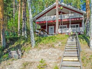 a house in the woods with stairs leading up to it at Holiday Home Aurinkoranta by Interhome in Hattusaari
