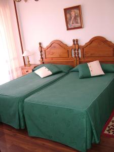 - un grand lit vert avec une couette verte dans l'établissement Hostal El Botero, à Cuzcurrita-Río Tirón